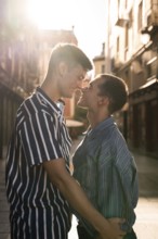 A gay couple embraces tenderly in the sunlit streets of Madrid, celebrating love and diversity. The