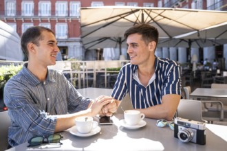 A gay couple shares a tender moment over coffee in the vibrant streets of Madrid. Capturing the