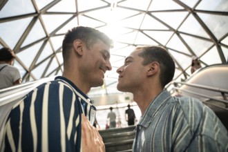 A gay couple shares a tender moment on the streets of Madrid. The sun sets behind them,