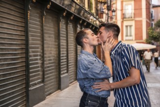 A gay couple shares a tender embrace on the vibrant streets of Madrid, reflecting love, equality,