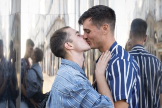 A joyful gay couple shares a tender kiss on the lively streets of Madrid. Their love and connection