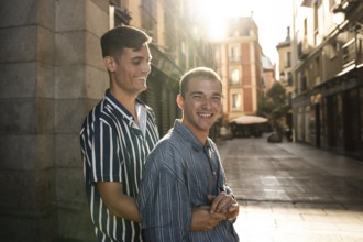 A joyful gay couple embraces while strolling down the sunlit streets of Madrid. Capturing love,