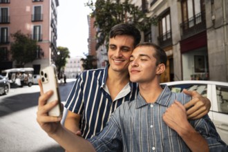 A gay couple happily takes a selfie while exploring the charming streets of Madrid. The vibrant