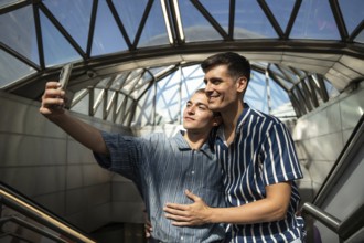 A joyful gay couple takes a selfie on the streets of Madrid. Their happy expressions capture a