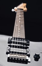 Close up of an electric guitar showcases sleek design and detailed focus on strings. Emphasizes