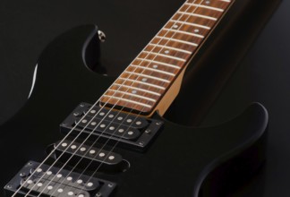 Detailed close up of an electric guitar focusing on its neck and pickups. The rich wood texture