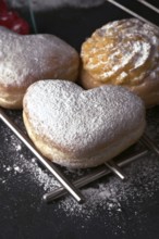 A close up of delectable heart shaped cream buns, generously dusted with icing sugar, presented on