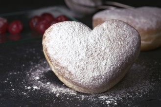 A delectable heart shaped cream bun generously sprinkled with icing sugar, presented on a rustic