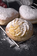 Close up view of scrumptious cream filled buns generously sprinkled with fine icing sugar,