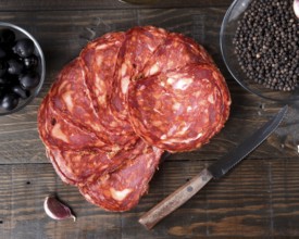 Delicious slices of spanish chorizo are artfully placed on a rustic wooden board. Accompanied by a