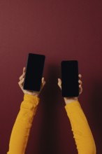 Side view of unrecognizable person in casual clothes holding smartphones with black screen while