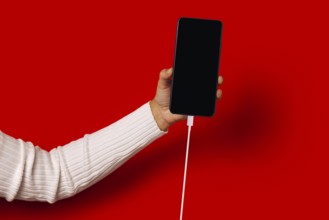 Side view of unrecognizable person in casual clothes holding smartphone with black screen while