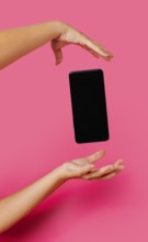 Crop anonymous person in casual clothes showing modern smartphone with empty screen while floating