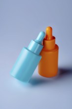 Two vibrant serum bottles in blue and orange hues are showcased against a soothing blue background,