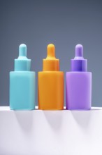 Three vibrant and colorful serum bottles aligned on a sleek surface with a soft gray gradient