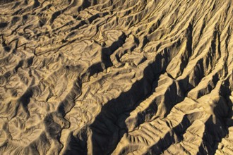 Aerial view of golden desert textures at Caineville Mesa, Utah. Features notable ridges and
