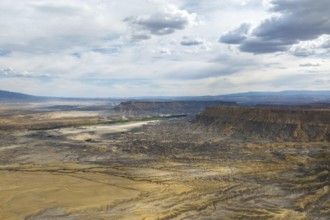 Aerial view of a rugged desert landscape under a dramatic, cloud filled sky in Hanskville, Utah.