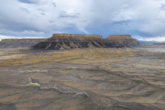 A breathtaking view of a desert plateau rising under a vast, cloudy sky, showcasing layers of