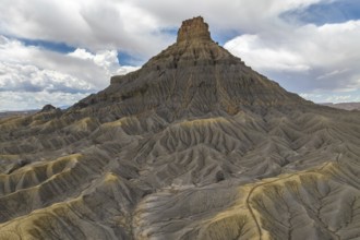 A striking desert mesa rises prominently against a backdrop of expansive clouds, showcasing