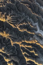 Aerial photo capturing golden desert textures and intricate patterns of Caineville Mesa, Utah. The