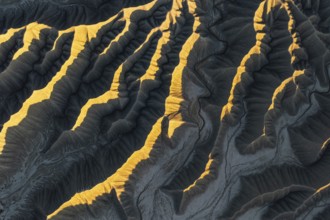 Aerial view of Caineville Mesa, Utah, showcasing dramatic ridges illuminated by golden sunlight.