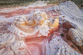 Aerial view of swirling rock formations in vibrant reds and whites in White Pocket, showcasing the