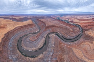 Captivating aerial view of a river winding through the dramatic, layered San Juan canyon. The