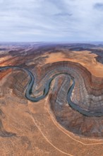 An aerial view captures a winding river cutting through a desert in San Juan canyon, showcasing