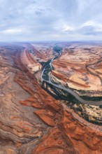 Aerial view showcasing a vibrant San Juan canyon with a winding river flowing through it. The scene