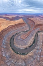 A stunning aerial view captures a serpentine river winding through layered rock formations in a