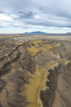 Aerial view of an expansive desert terrain featuring rugged formations and soft sand hues in