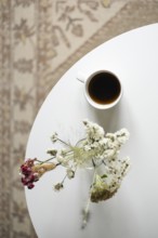 Top view of a tranquil setting featuring a bird's-eye view of a white cup filled with coffee beside