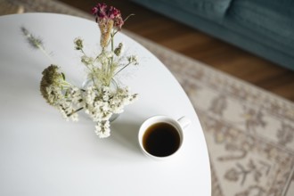 Top view of a serene home scene featuring a cup of black coffee and a vase of delicate dried