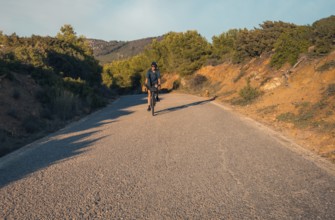 Male cyclist descending a lush mountain road, located in Zahara de los Atunes, Cadiz, capturing the
