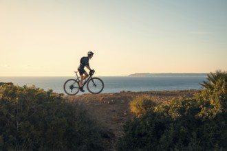 A young male cyclist rides along a scenic coastal path in Zahara de los Atunes, Cadiz, with the