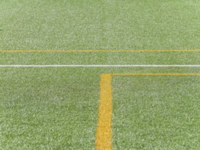 A close up view of vibrant green artificial turf with distinct yellow and white lines, creating