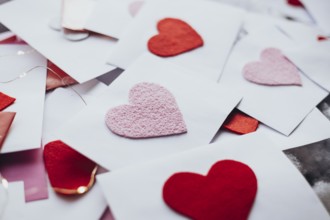 A variety of red and pink felt hearts adorn envelopes, evoking a romantic Valentine's Day
