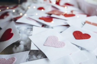 A collection of handmade Valentine's Day cards with red hearts on white envelopes, scattered