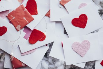 Valentine's Day envelopes adorned with red and pink felt hearts, scattered elegantly among fairy