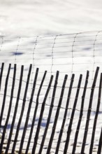 A rustic wooden fence stands in contrast against a serene snowy backdrop, showcasing a blend of