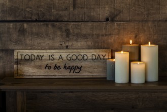 A motivational sign with the words Today is a good day to be happy rests on a rustic wooden shelf,