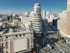 A bustling urban Madrid scene captures the vibrant life of Gran Via street flanked by historic