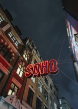 A vibrant neon Soho sign illuminates the street below, contrasting against a dark, moody London