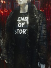 A fashionable mannequin in a London storefront displays a black faux fur coat and a sparkling