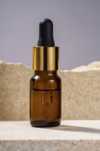 A stylish amber glass serum bottle with a black dropper and golden details, showcased on a textured