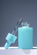 A striking image featuring a turquoise serum bottle with a glass dropper filled with liquid, set