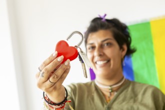 A joyful transgender woman holds keys and a heart lock, symbolizing a new beginning in her home. A