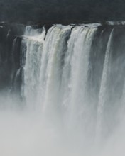 Mist surrounds the powerful, cascading waters of Iguazu Falls located on the border of Argentina