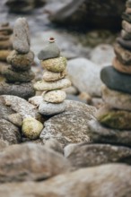 A stack of balanced stones on a rocky surface in a peaceful outdoor setting besides the sea.