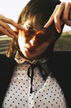 Woman in polka dot blouse, holding film strip against sunlight, creating an artistic shadow over